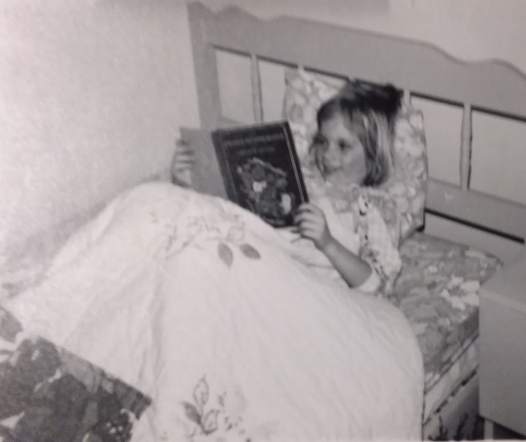 Christine, at 6 years old, reading in bed